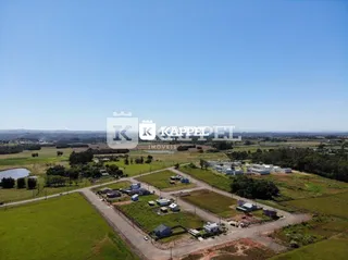 Vista aérea de um terreno rural com áreas verdes e construções dispersas.