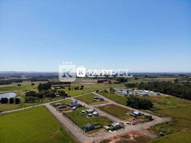 Vista aérea de um terreno rural com áreas verdes e construções dispersas.