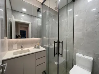 Banheiro moderno com box de vidro e revestimento claro.