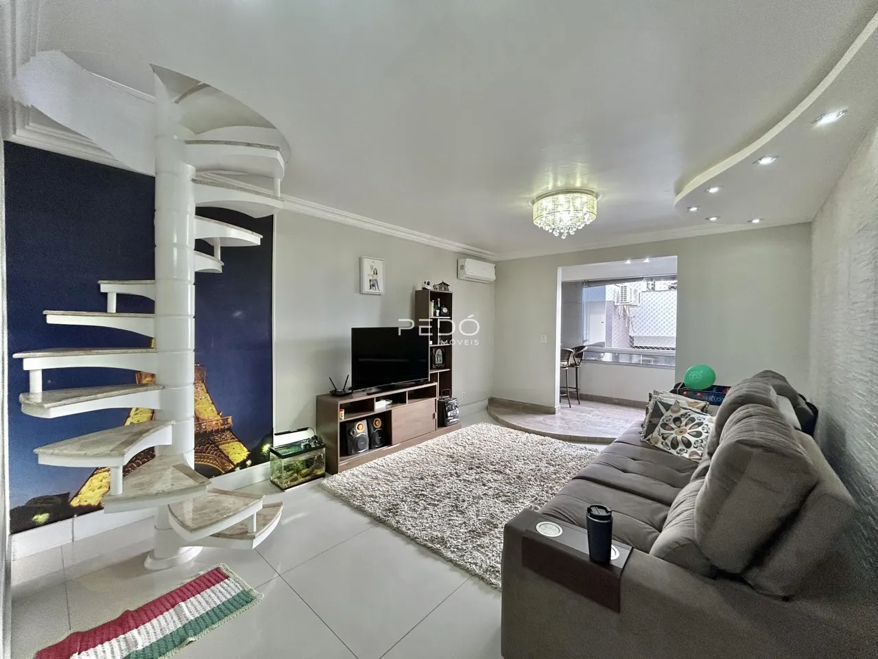 Sala de estar com escadaria e sofá em ambiente claro.