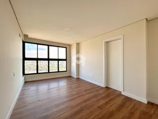 A sala apresenta piso de madeira e uma grande janela com vista da cidade.
