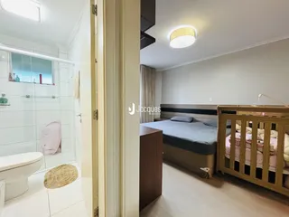 Quarto com cama de madeira e banheiro adjacente em imóvel no Brasil.