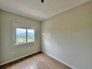 Ambiente interno de uma sala com piso de madeira e janela com vista para a paisagem.