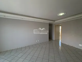 Vista interna de um corredor com piso de cerâmica clara e paredes cinzas.