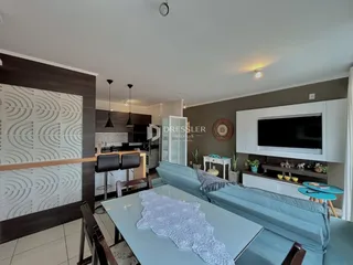 Sala de estar moderna com sofá azul e área de jantar em um apartamento.
