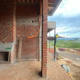 Parede de tijolos vermelhos com estrutura de madeira visível em uma construção.