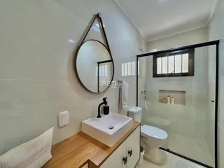 Banheiro com bancada de madeira e box de vidro.