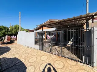 Fachada de uma residência com portão de ferro e piso de ladrilhos na frente.