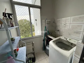 Vista interna de um cômodo com janela e máquina de lavar roupa.