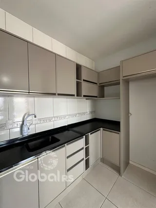 Vista interna de uma cozinha com armários e bancadas em tom neutro.