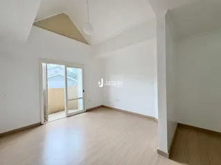 Ambiente interno de uma sala com piso de madeira clara e paredes brancas.