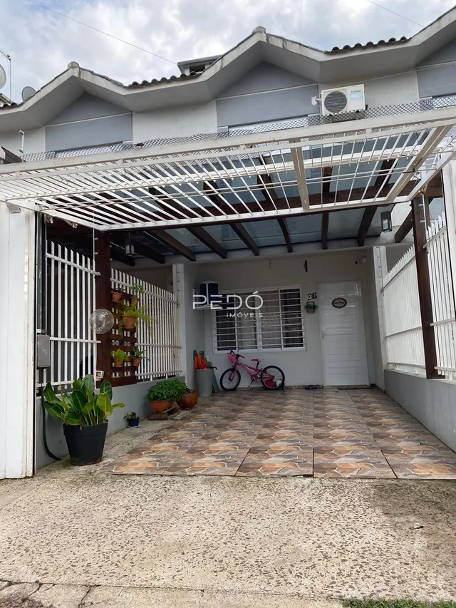Fachada de casa com área coberta e muro branco em Lajeado.
