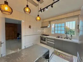 Vista da cozinha com armários e piso de cerâmica branca.