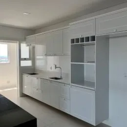 Armários brancos com bancadas e espaço de armazenamento são visíveis na cozinha.