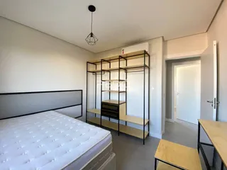 Quarto com cama e estante de metal em ambiente claro.