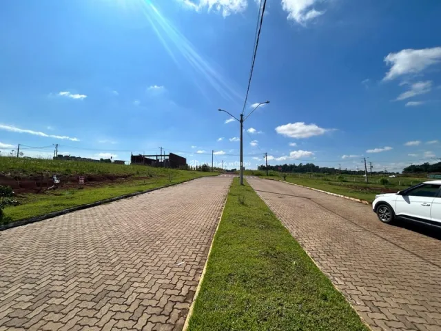 Vista de uma estrada pavimentada com grama nas laterais sob um céu azul.