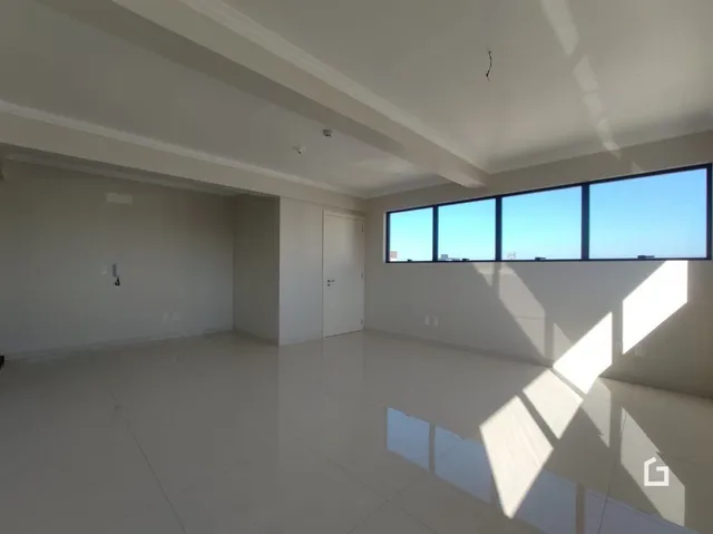 Ambiente interno de uma sala com piso claro e grandes janelas.