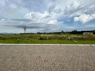 Vista externa de uma área pavimentada com grama e céu nublado.