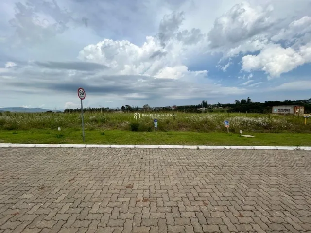 Vista externa de uma área pavimentada com grama e céu nublado.
