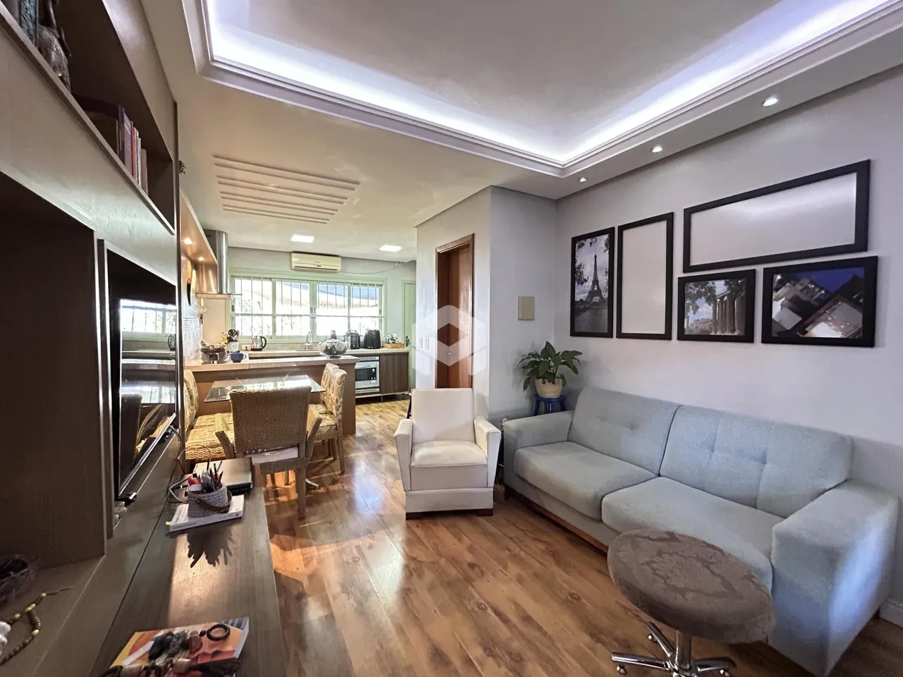 Sala de estar com piso de madeira e decoração moderna em Lajeado.