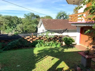 Vista externa de uma residência com jardim e cerca de madeira.