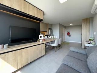 Sala de estar e cozinha moderna com ilha de madeira e sofá cinza.