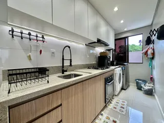 Cozinha moderna com armários brancos e bancada clara.