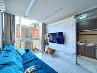 Sala de estar com sofá azul e grande janela de vista para o exterior.