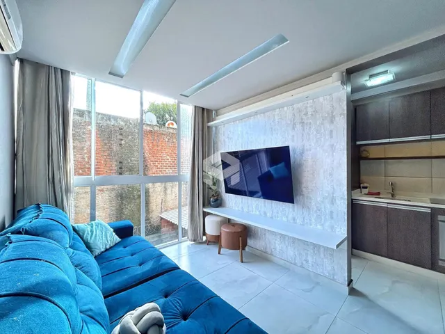 Sala de estar com sofá azul e grande janela de vista para o exterior.