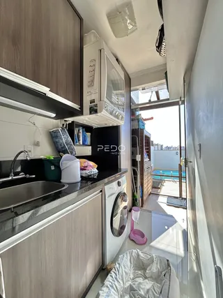 Vista da cozinha com bancada escura e armários modernos.