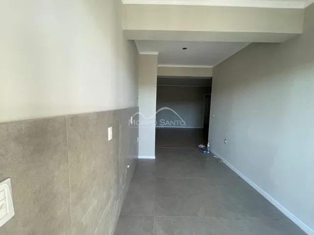 Corredor interno com paredes brancas e piso cinza.