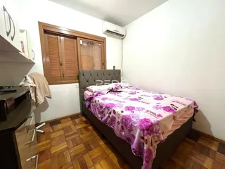 Quarto com cama e piso de madeira no interior da residência.
