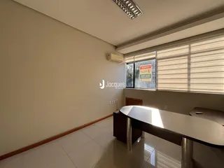 Ambiente interno de uma sala ampla com piso de cerâmica e janela.