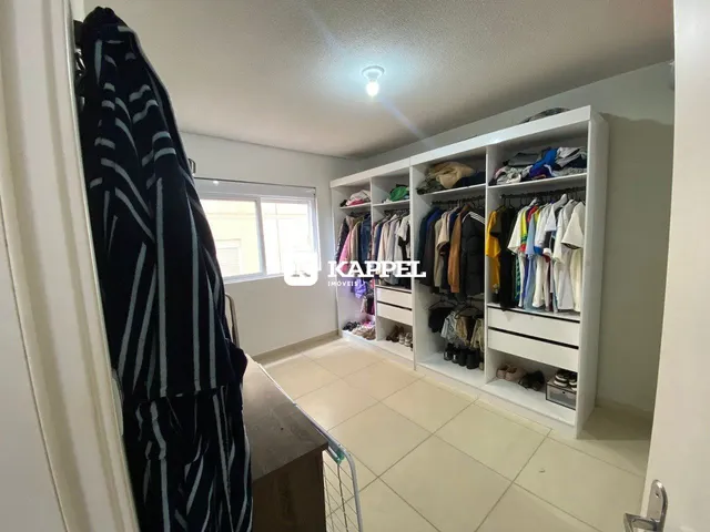 Interior de um quarto com estantes brancas preenchidas com roupas.