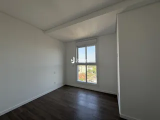 A sala apresenta paredes brancas e piso de madeira.