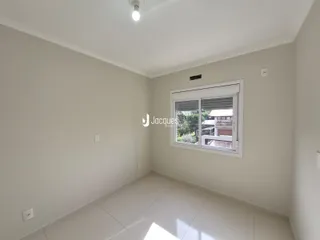 Uma sala de estar vazia com paredes brancas e piso claro.