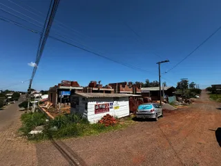 Vista externa de estruturas de tijolos em uma área rural com estrada de terra.