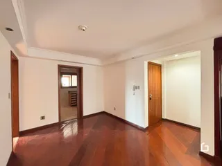 Sala de estar com piso de madeira escura e paredes brancas.