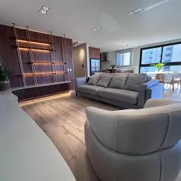 Uma sala de estar com sofá e piso de madeira clara.