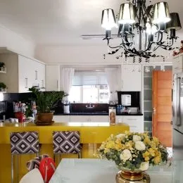 Foto de uma cozinha com bancada amarela e armários brancos.