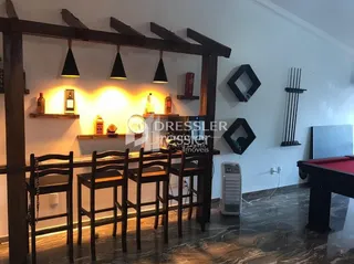 Interior de uma sala com móveis de madeira escura e bancos.