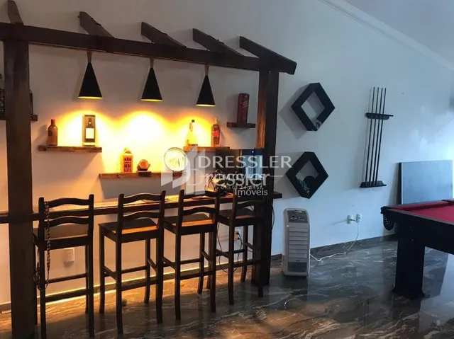 Interior de uma sala com móveis de madeira escura e bancos.