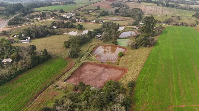 Vista aérea de uma propriedade rural com campos abertos e áreas de água no entorno.
