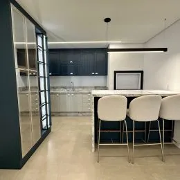Sala de estar com armários escuros e ilha central em ambiente moderno.