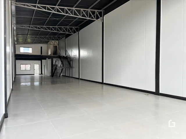 Corredor interno de uma propriedade com estrutura metálica exposta.