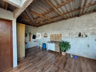 Foto do interior de uma sala com piso de cerâmica e vigas de madeira expostas.