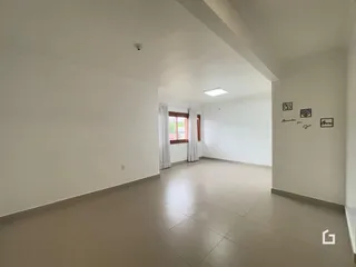 Corredor interno de uma residência com paredes brancas e piso de cerâmica.