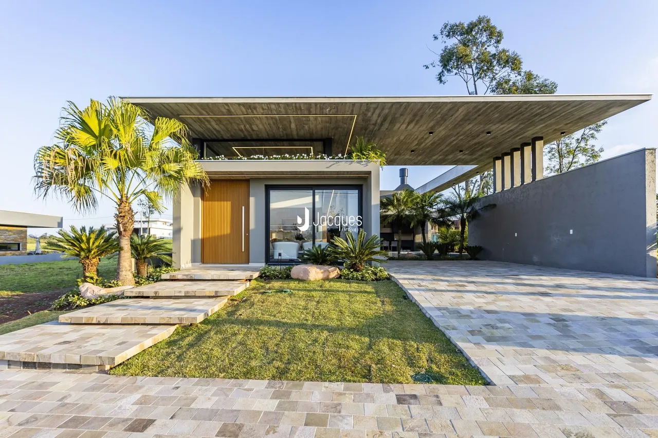 Vista da fachada moderna de uma casa em Lajeado, Brasil, com jardim e área externa pavimentada.