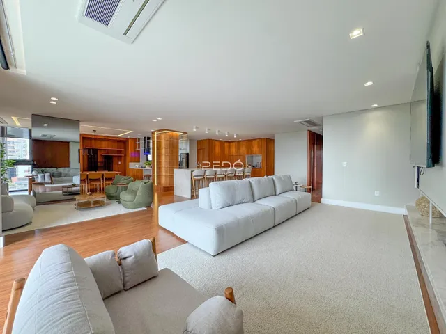 Sala de estar ampla com piso de madeira e sofá claro.