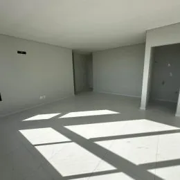 Vista interna de um ambiente com piso claro e sombras projetadas no chão.